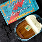 An open can of Mevalco Don Bocarte Cantabrian Anchovies with decorative label on a dark background