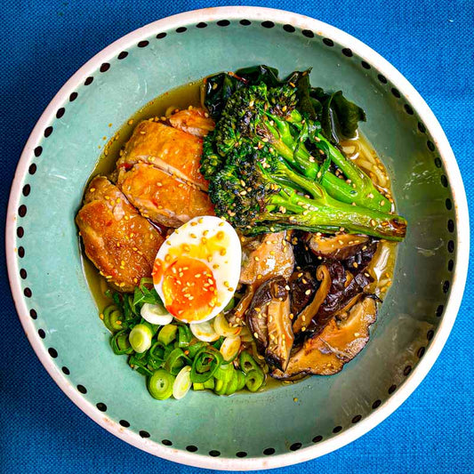 Bowl of Japanese Ramen with crispy chicken, broccoli, boiled egg and spring onions