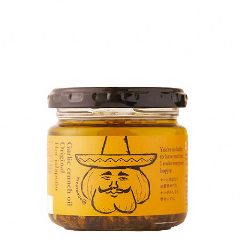 A 110g glass jar of Odawaraya garlic crunch oil with jalapenos with a black screw-on lid and an orange label featuring a cartoon illustration of a bearded man in a sombrero.